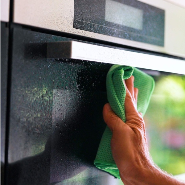 Glas van keuken apparaten schoonmaken met de glasreiniger van GEWELDIGSCHOON